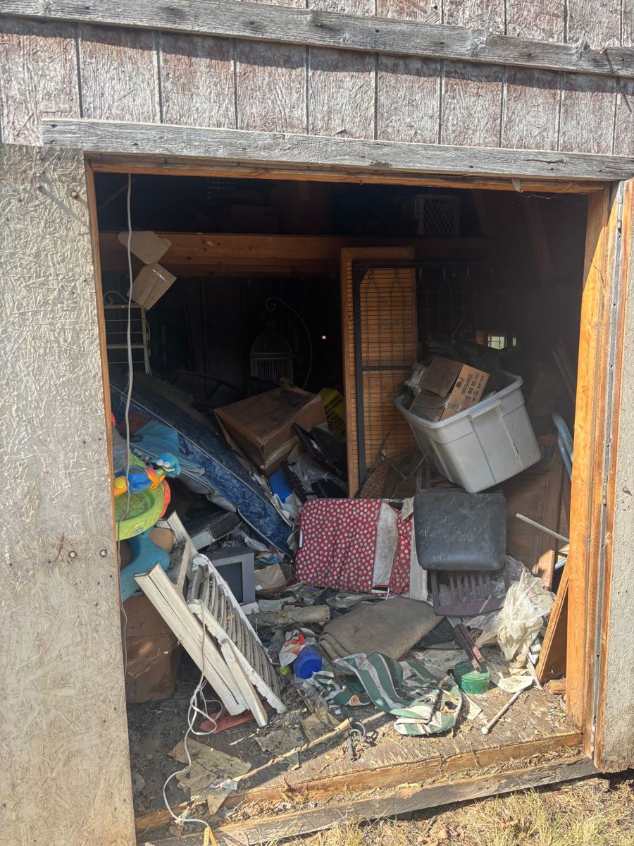 Barn cleanout before: packed with boxes, a mattress, furniture and debris